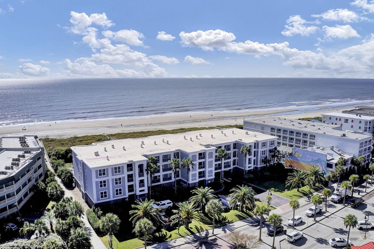 Aerial view of 1140 Ocean Blvd from ocean with beach, pier, and neighboring condos