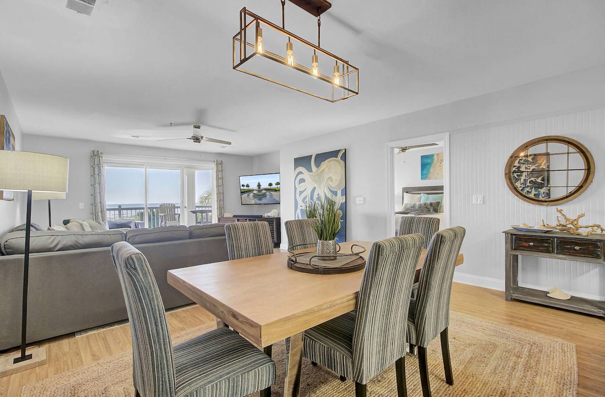 Dining and living area from kitchen — striped chairs, octopus painting, and ocean views