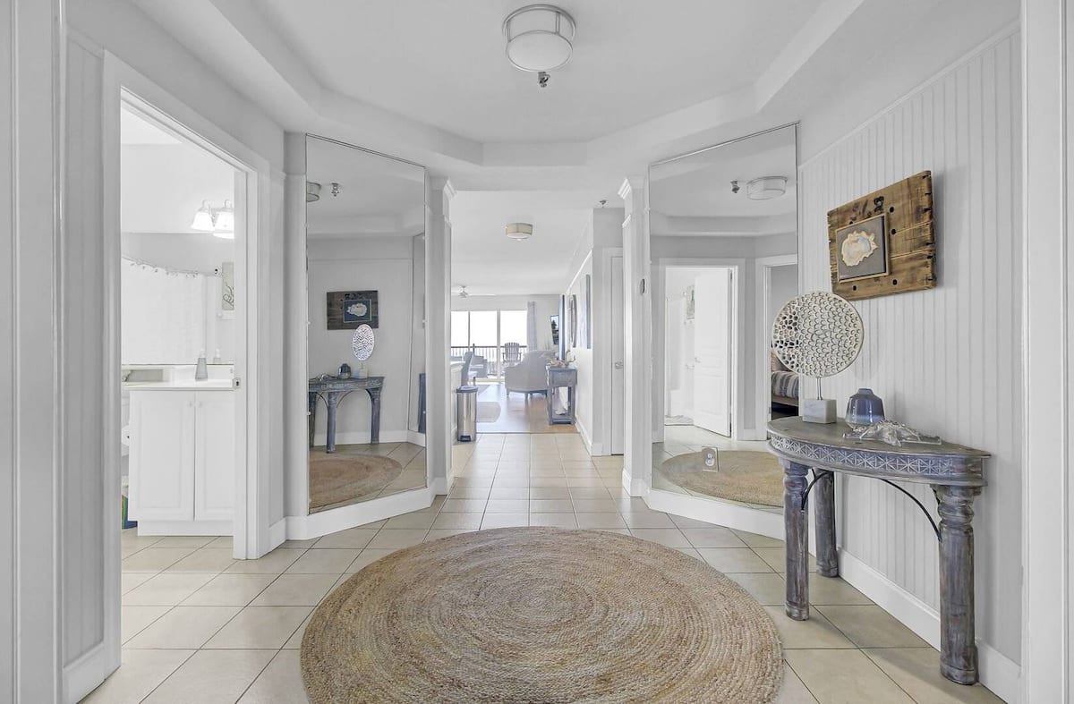 Spacious foyer with archway columns, jute rug, coral decor, and view to living area