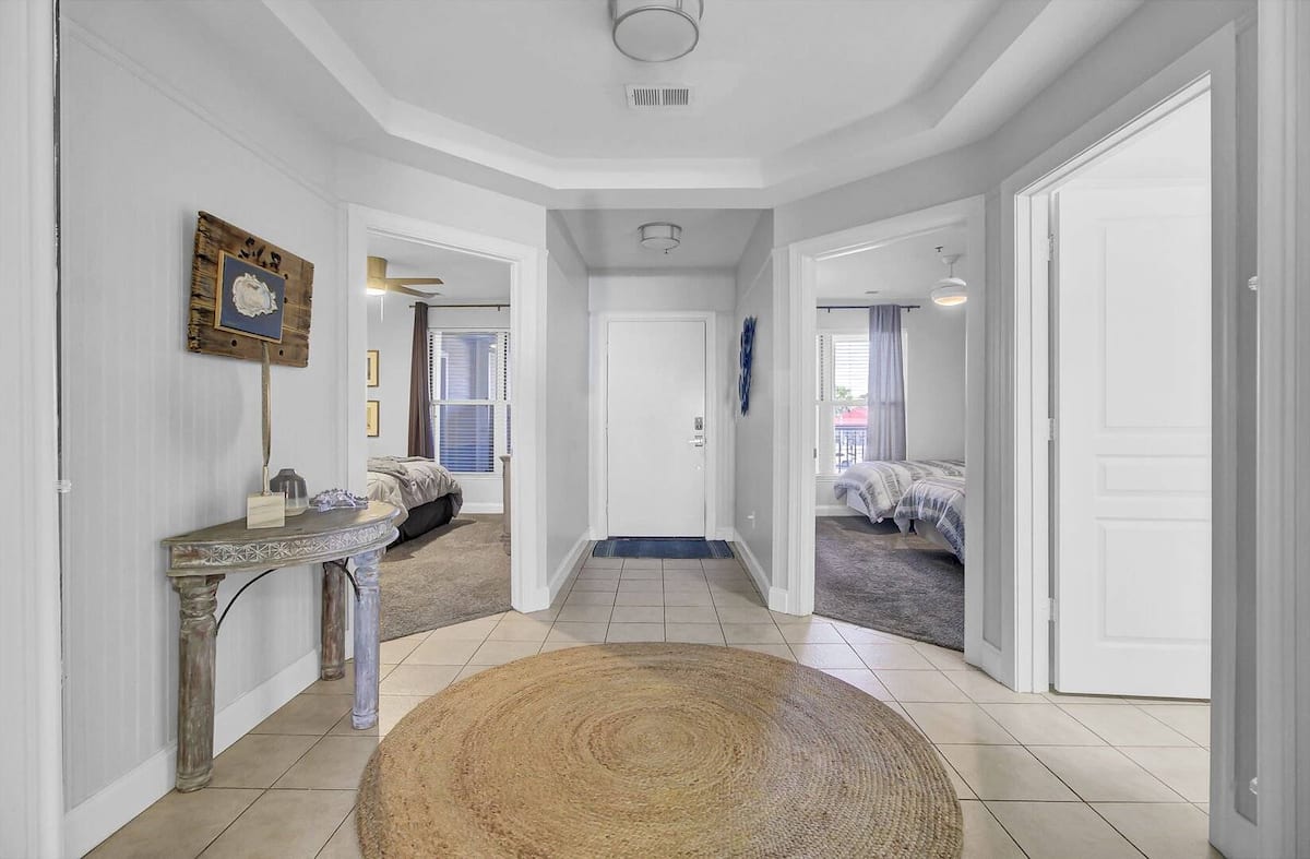 Entry foyer with jute rug, coastal console table, beadboard walls, bedroom views