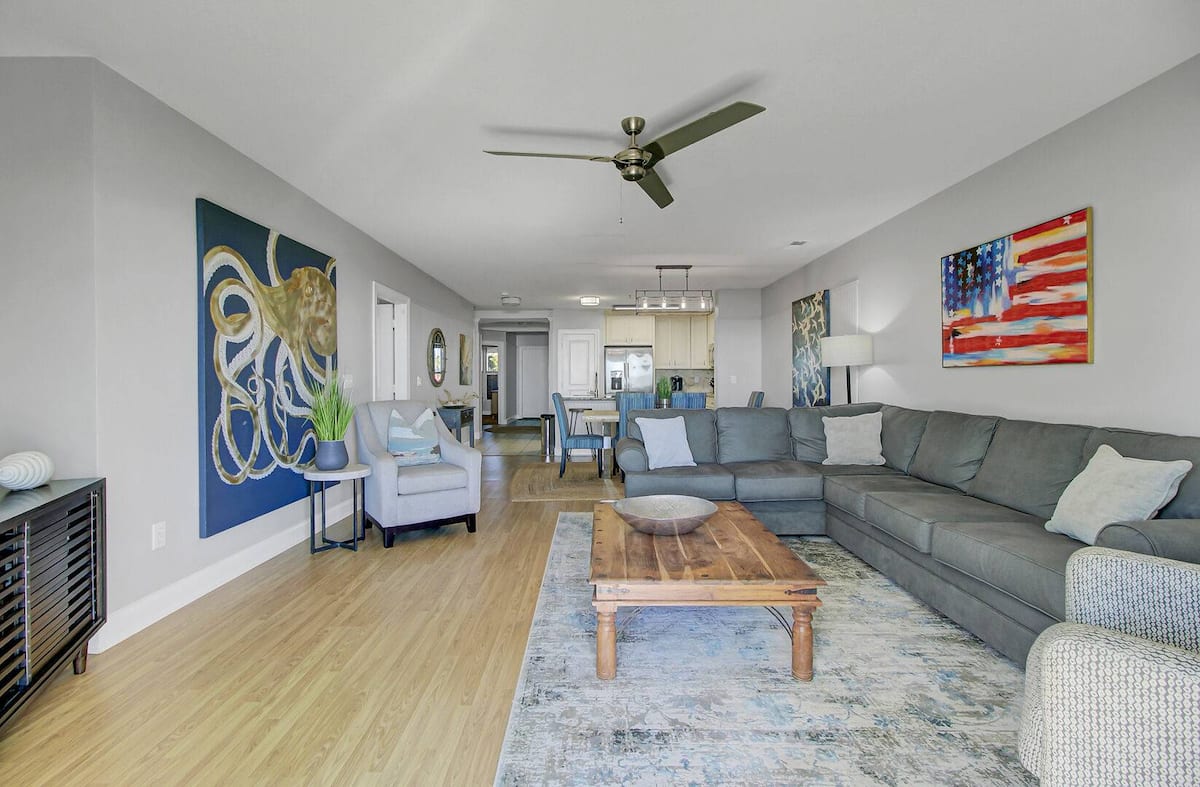 Wide-angle view of open floor plan — octopus art, flag painting, sectional, dining beyond