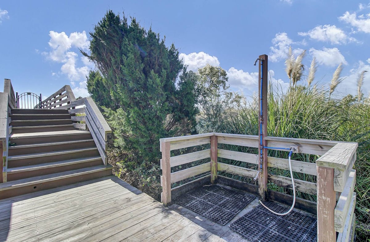 Outdoor shower on deck with stairs to beach boardwalk, cedar trees and pampas grass