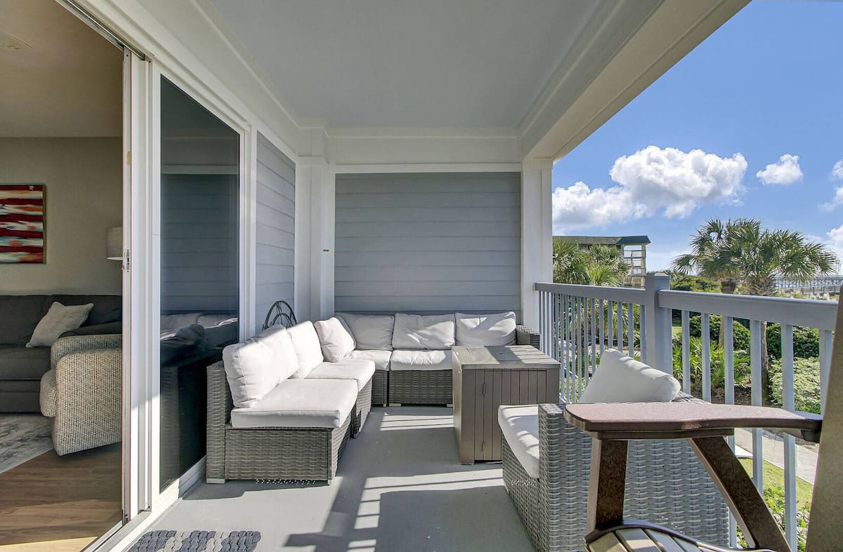 Covered patio with wicker sectional, white cushions, sliding doors to living room