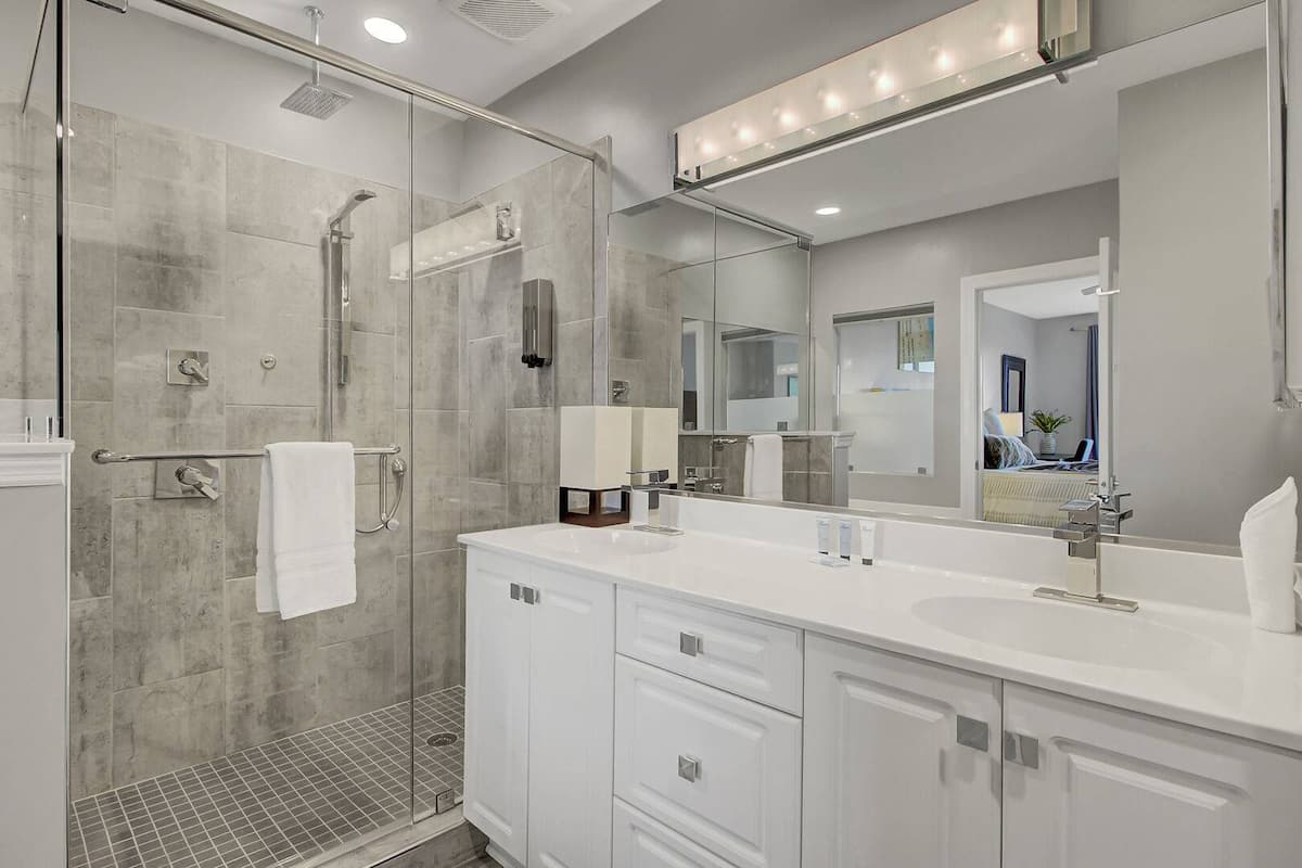 Primary ensuite with walk-in glass shower, dual vanity, and chrome fixtures