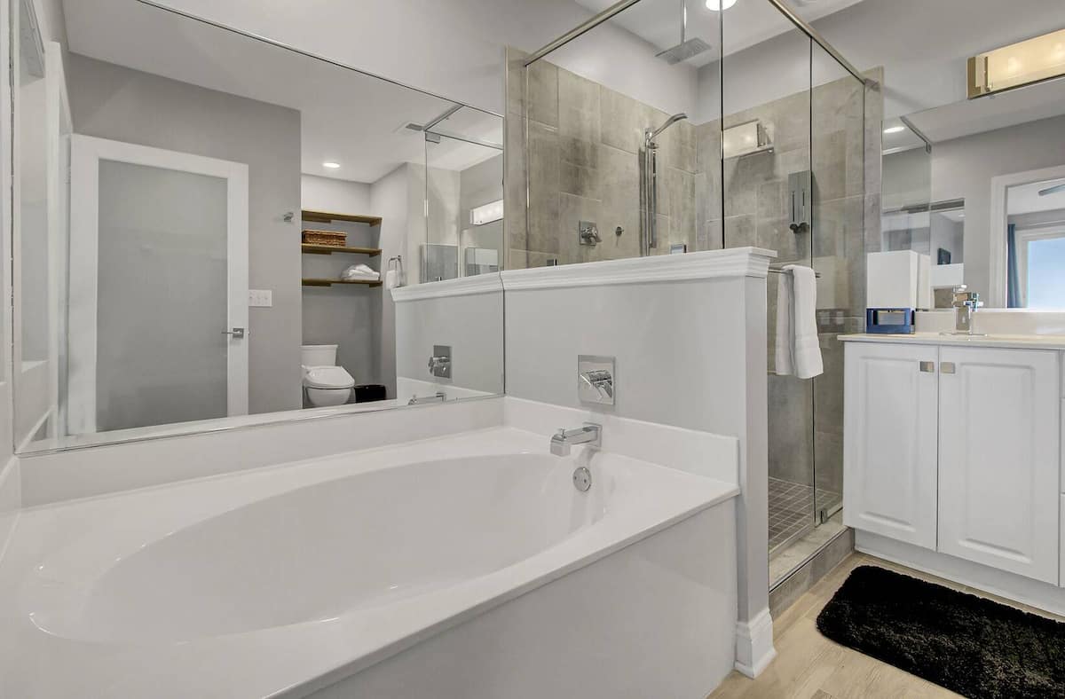 Primary bathroom with deep soaking tub, separate glass shower, and white vanity