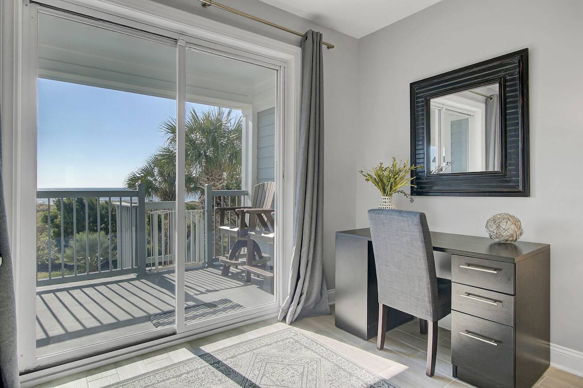 Primary bedroom sitting nook with desk, mirror, and sliding door to balcony with ocean