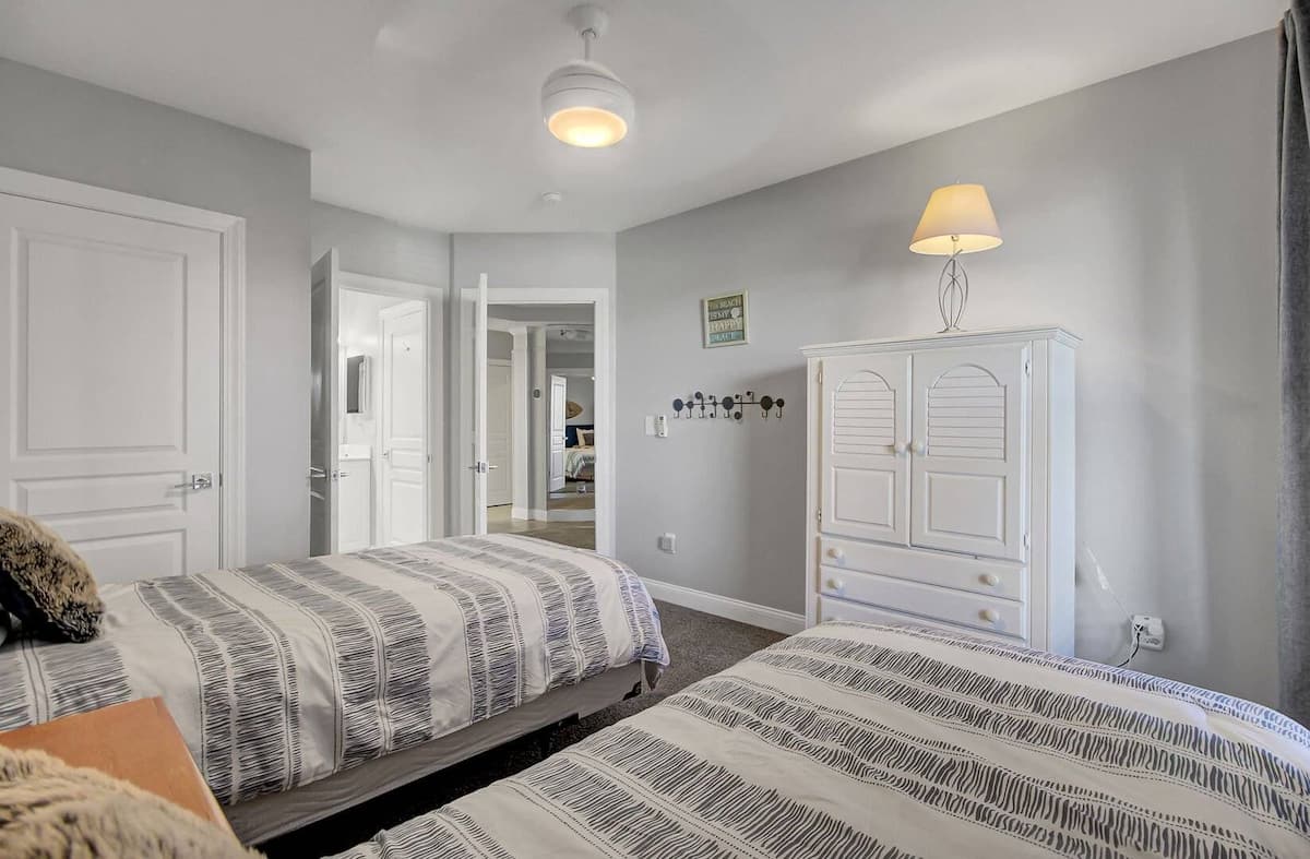 Third bedroom with twin beds, white armoire, and ensuite bathroom visible