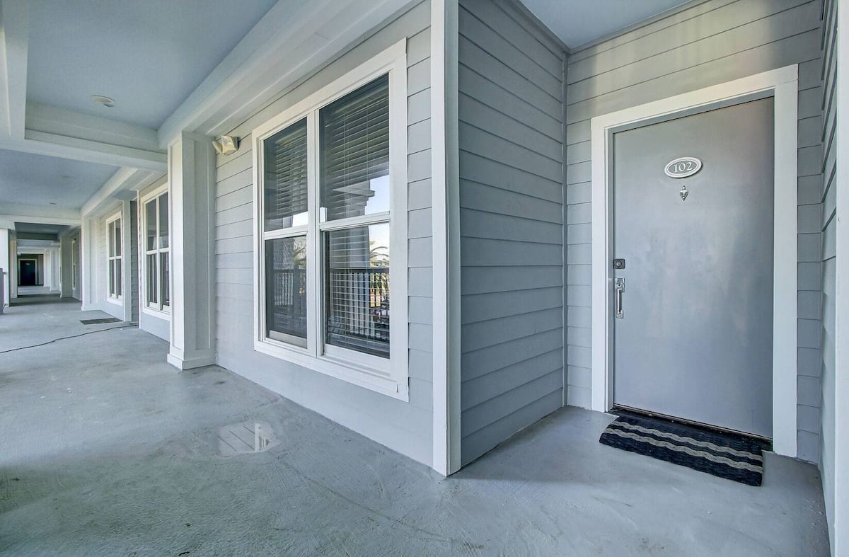 Ground-floor entrance to Unit 102 with covered breezeway and welcome mat