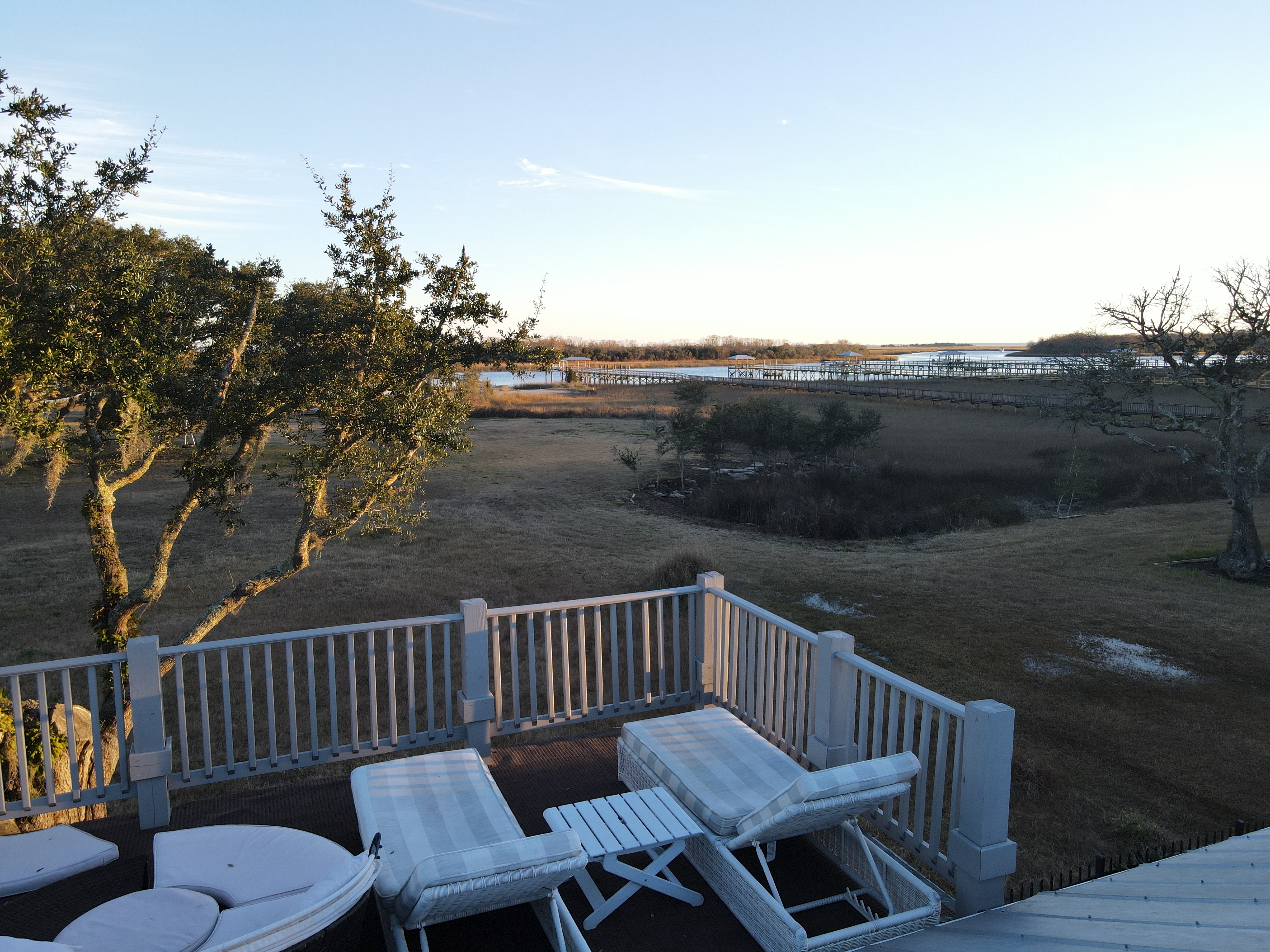 Elevated view from the upper deck across Spanish moss-draped oaks, golden marsh grass, and the Intracoastal Waterway at golden hour